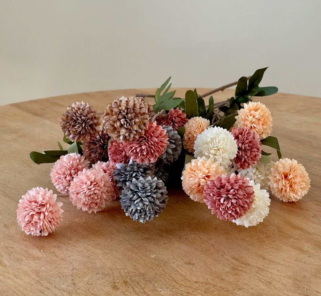 Colorful bouquet of chrysanthemum flowers on a wooden surface with a plain background